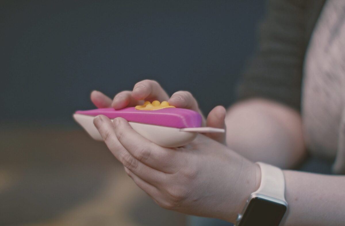 A person runs their fingers over the device's raised nodules